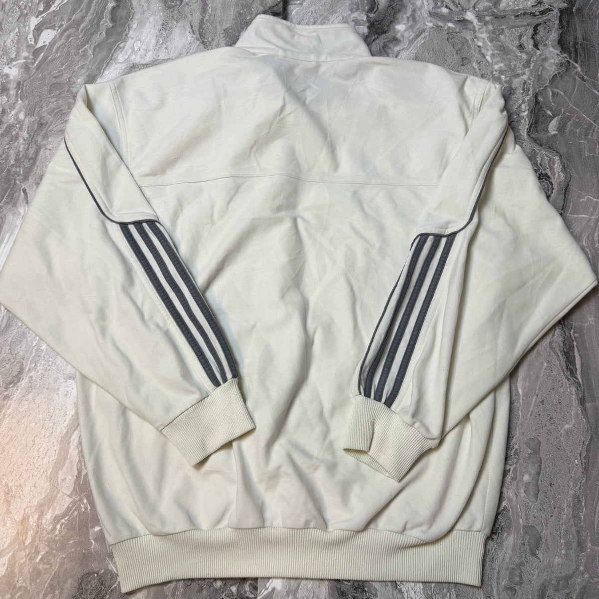 Dos de la veste Adidas blanche avec 3 bandes grises sur les manches
