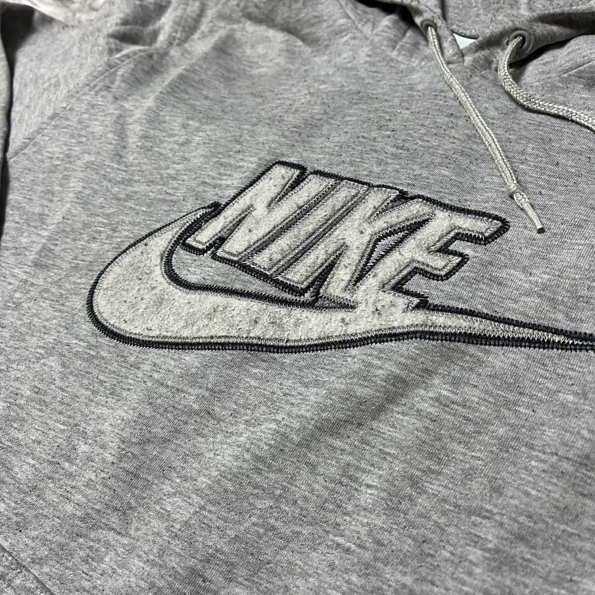 Détail du logo Nike brodé en relief sur le sweat gris