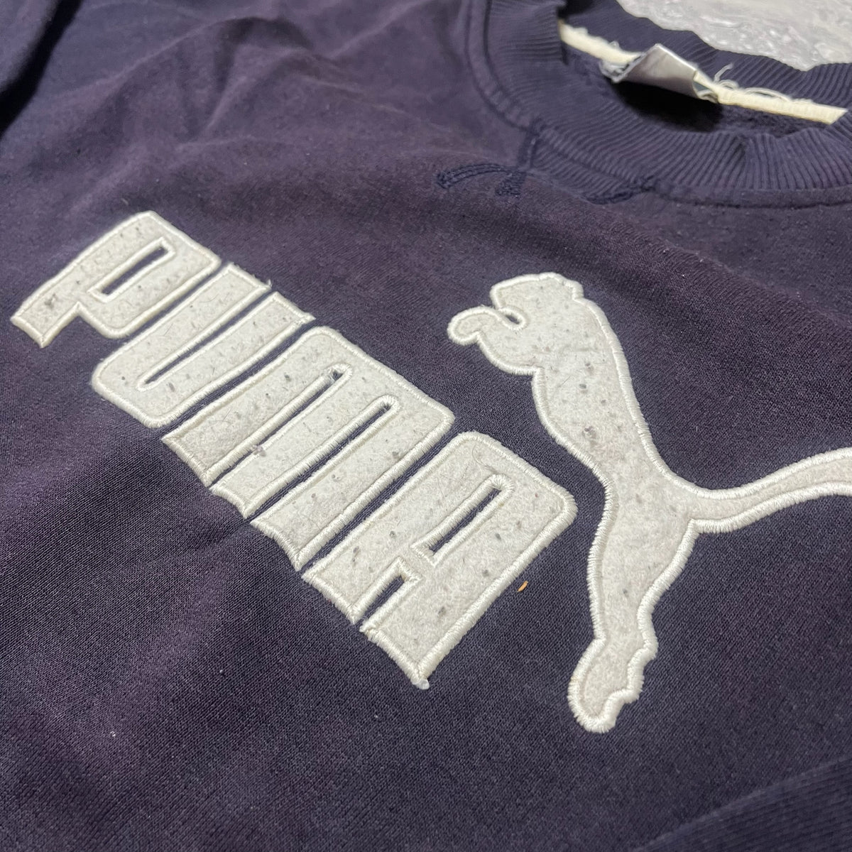 Détail du logo blanc en relief sur le sweat Puma bleu marine