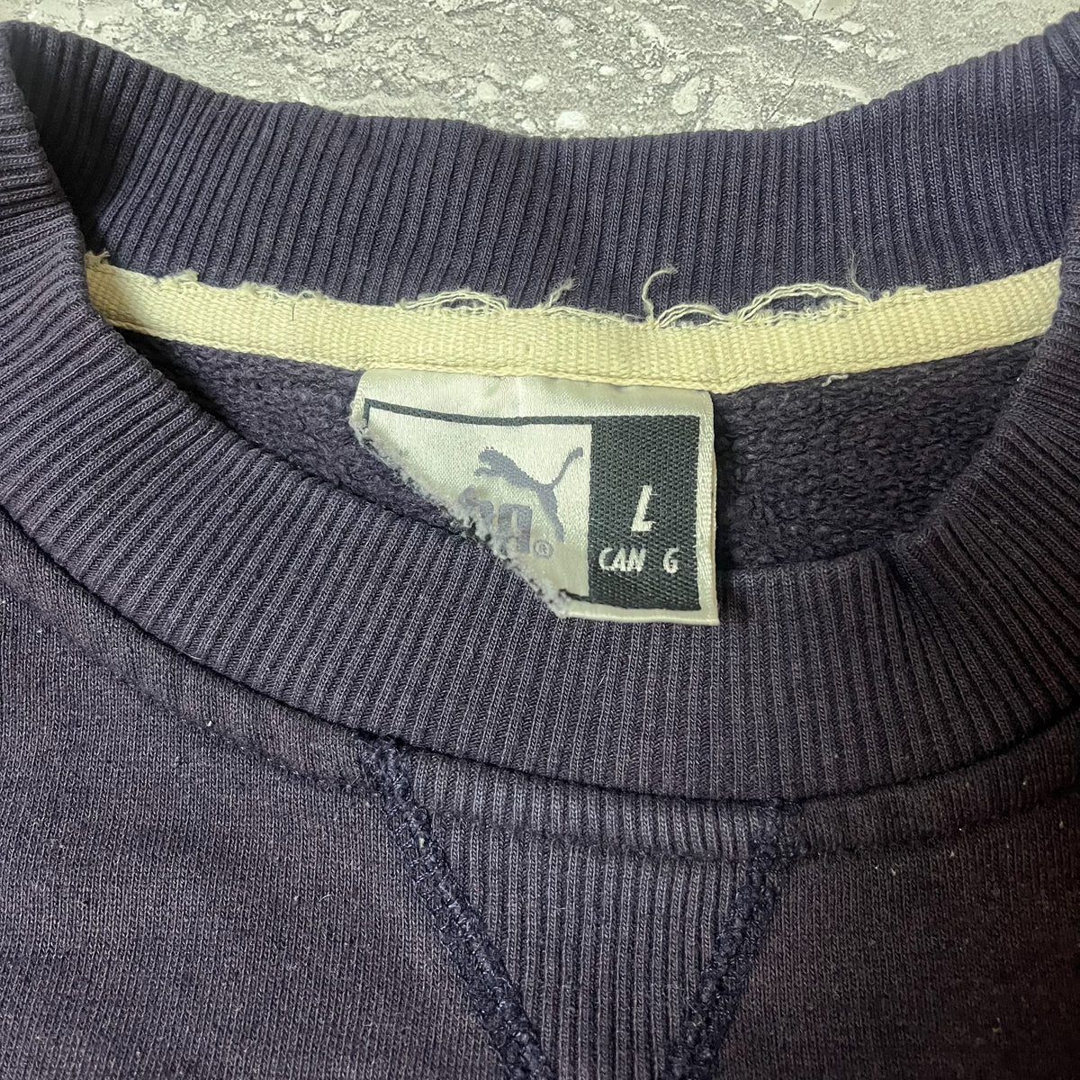 Étiquette Puma indiquant la taille L sur sweat bleu marine