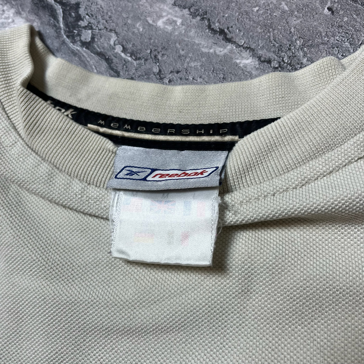 Étiquette Reebok blanche sur sweat beige