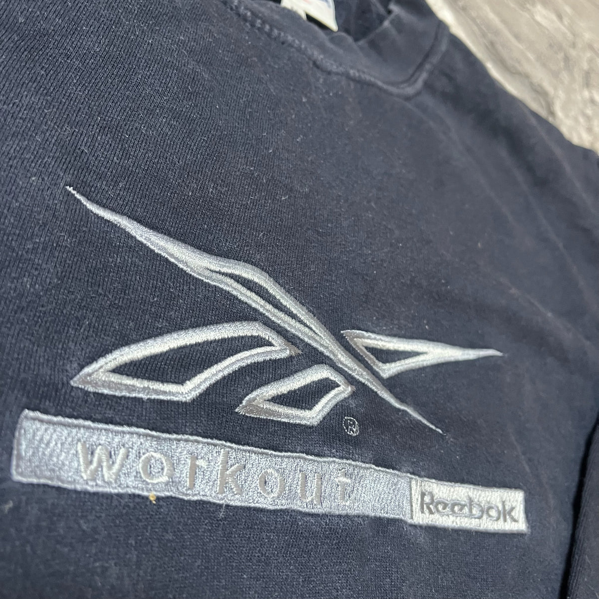 Détail du logo Reebok workout brodé argenté sur sweat noir