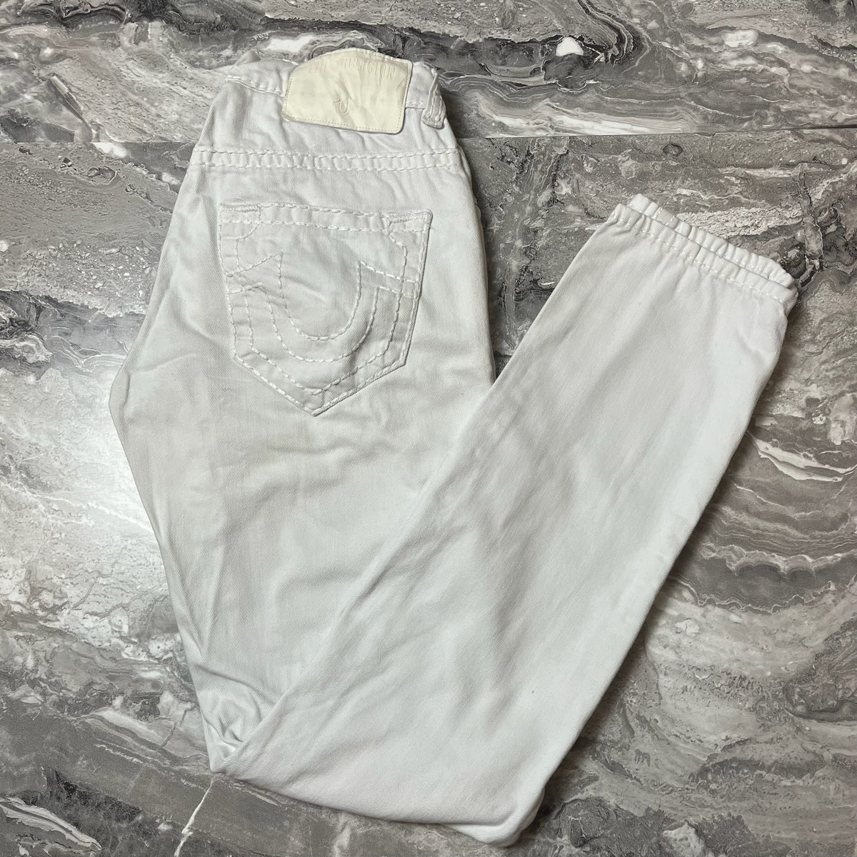 Jean True Religion blanc plié sur sol gris