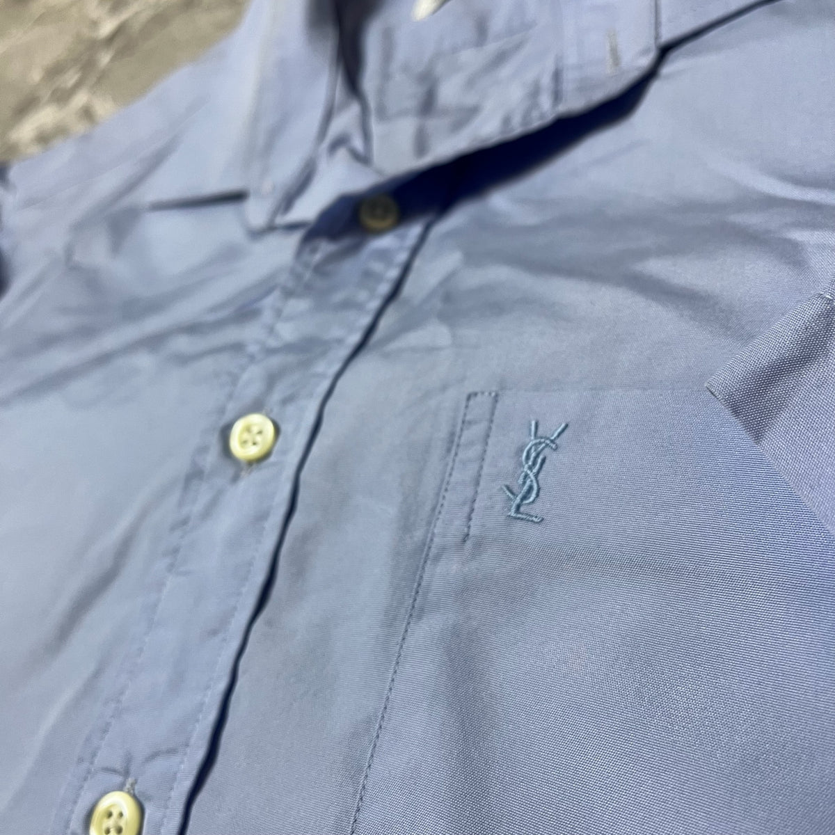 Détail du logo YSL brodé sur la poche de la chemise bleue