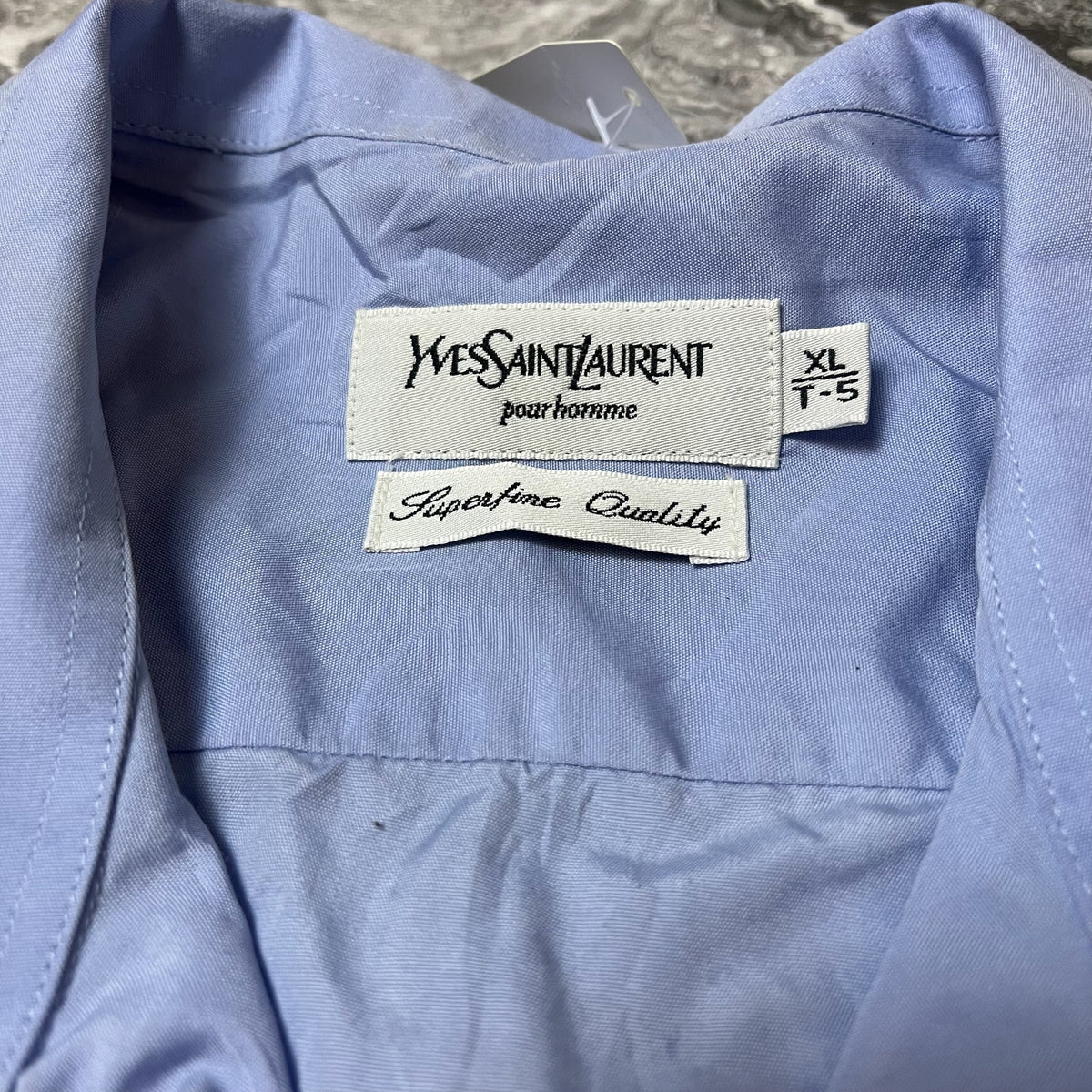 Étiquette taille XL et marque Yves Saint Laurent sur la chemise bleue