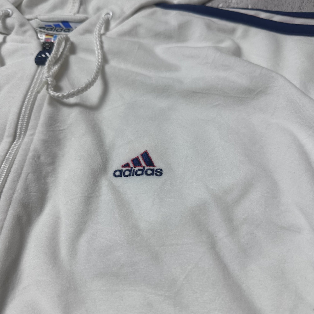 Détail du logo brodé Adidas sur le sweat blanc