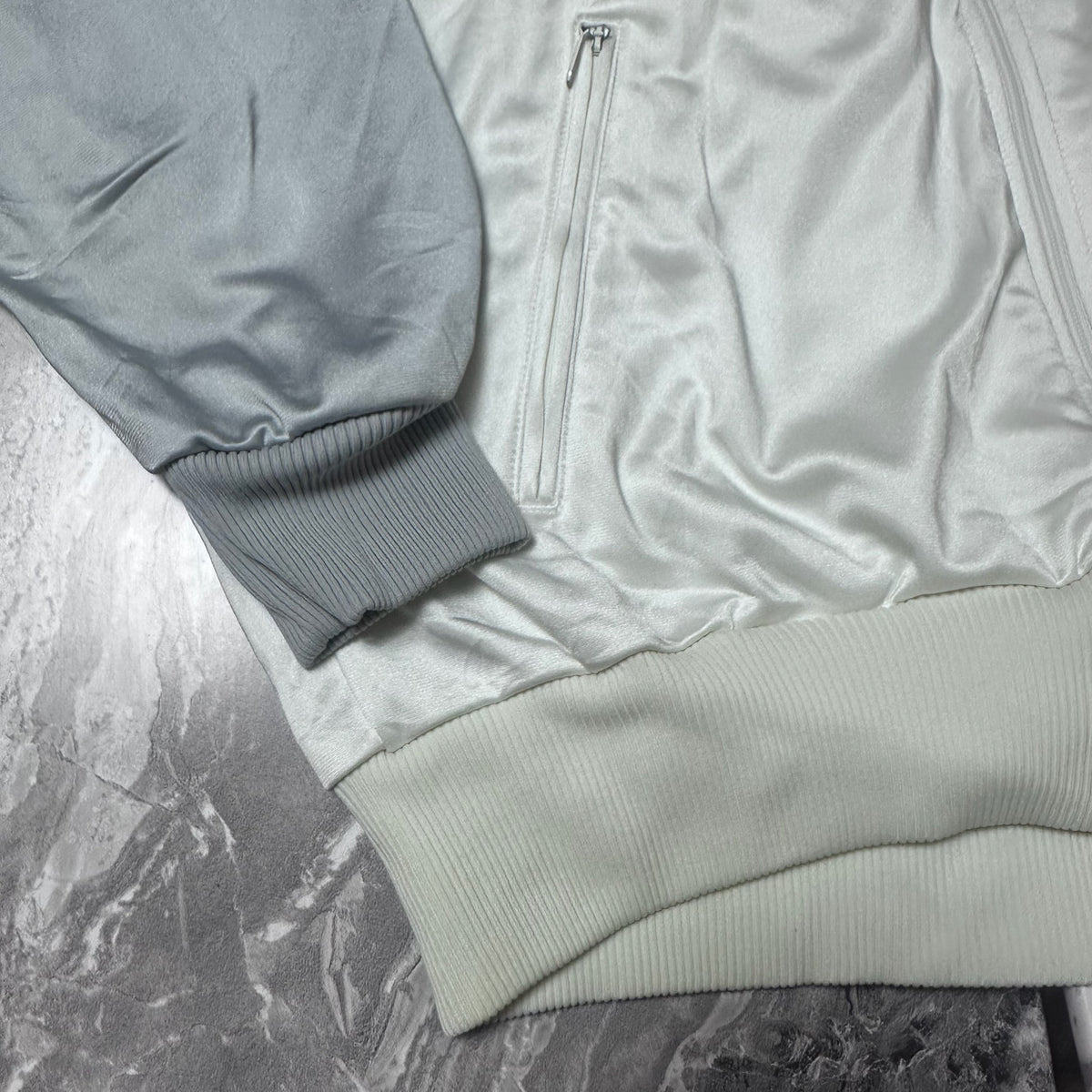 Détail du poignet et tissu de la veste Adidas blanche