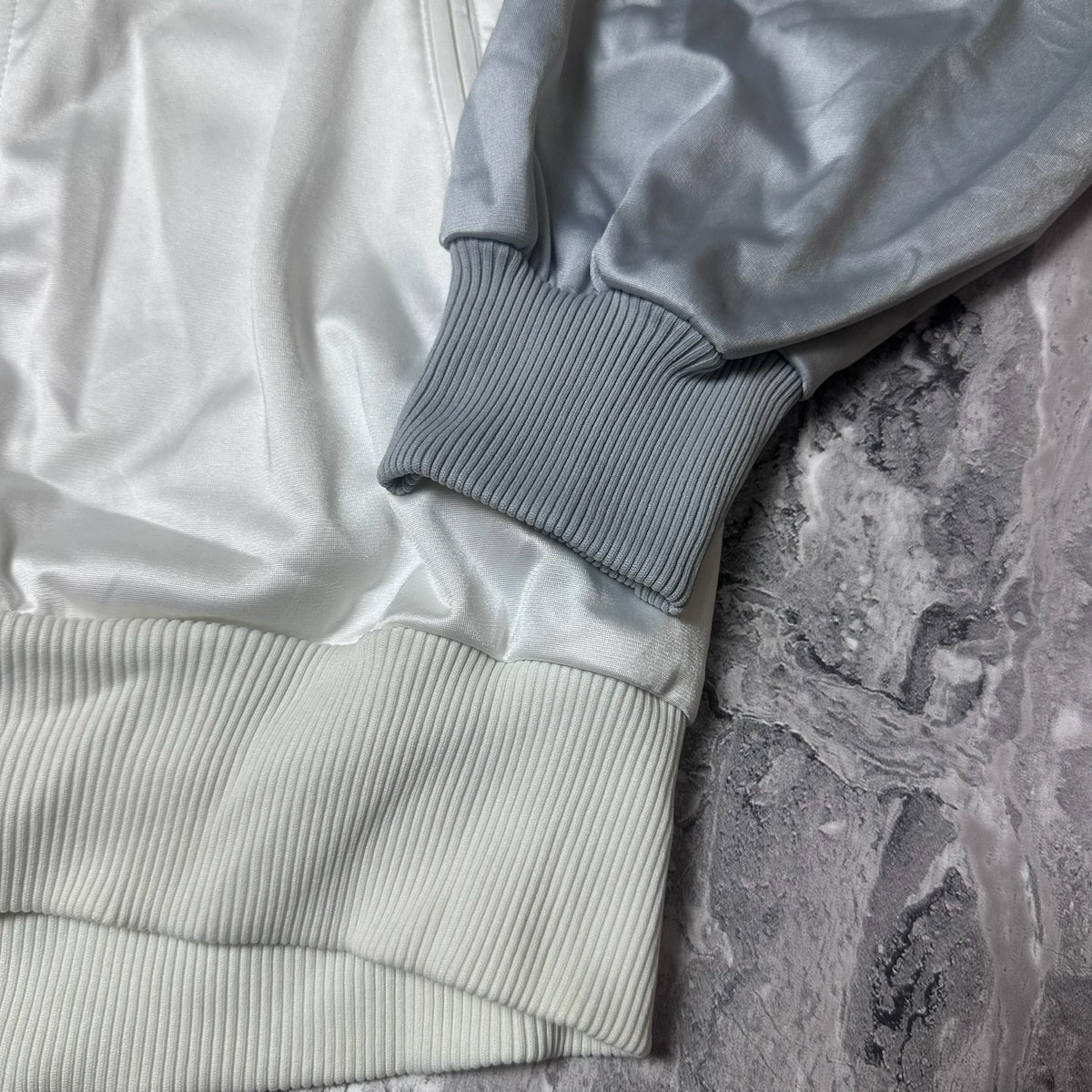 Poignet côtelé gris de la veste Adidas avec tissu blanc
