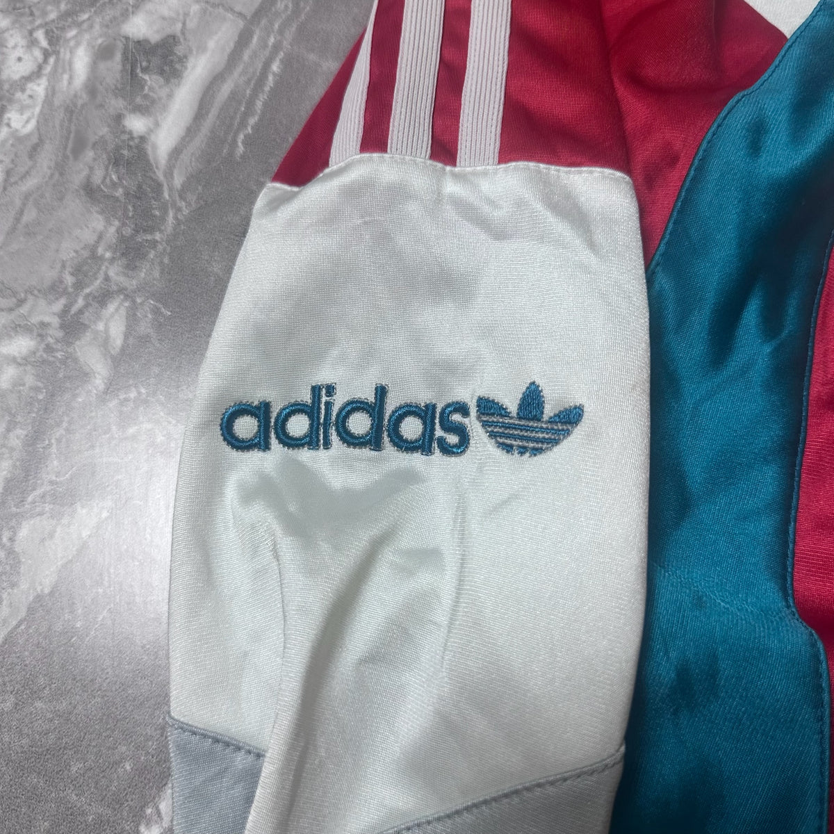 Broderie logo Adidas bleu sur la manche droite de la veste