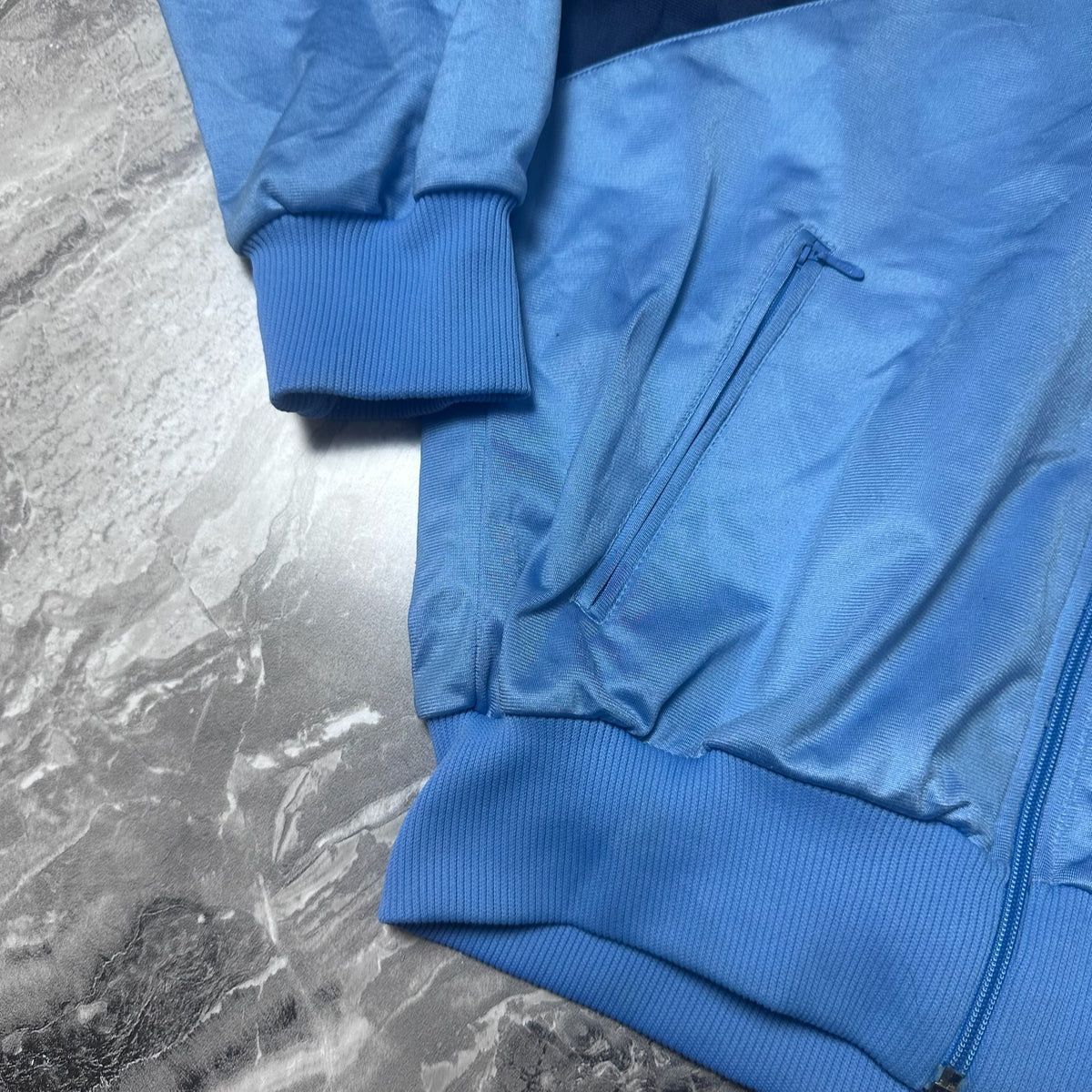 Détail poignet et poche zippée de la veste Adidas bleu