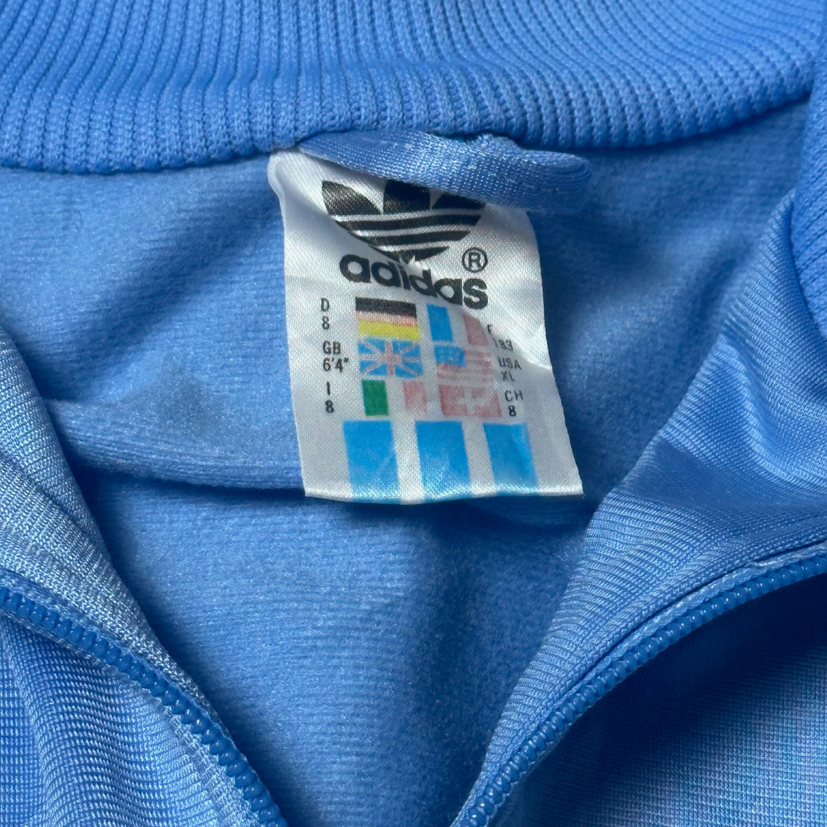 Dos de la veste Adidas bleu à bandes blanches et bleu marine