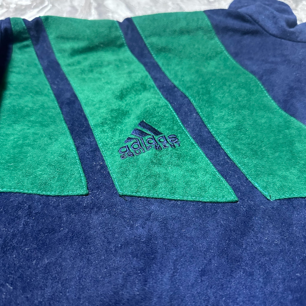 Détail du logo Adidas brodé avec les bandes vertes