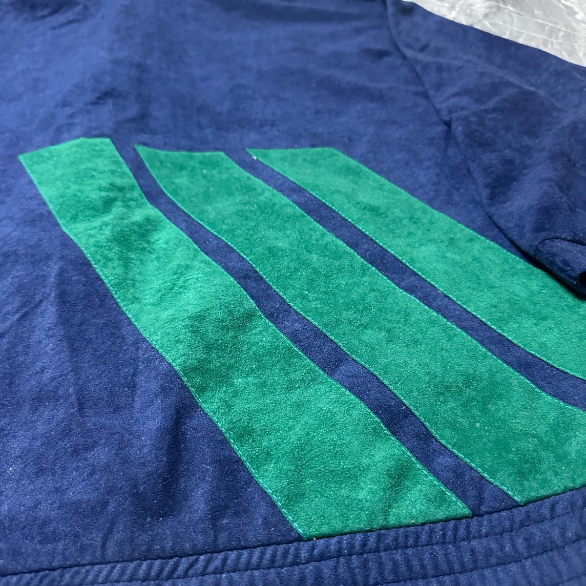 Détail des bandes vertes en velours sur la veste Adidas