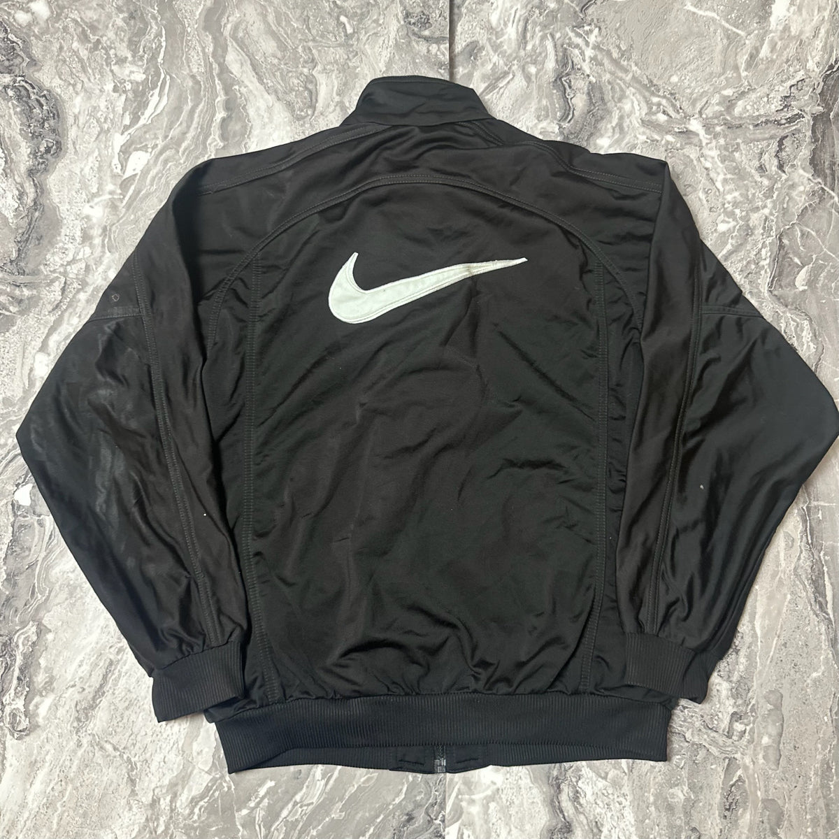 Dos de la veste Nike noire avec grand logo swoosh blanc