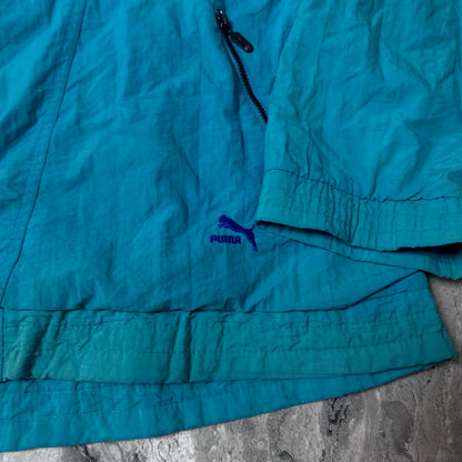 Détail du logo Puma brodé près de la poche de la veste bleue