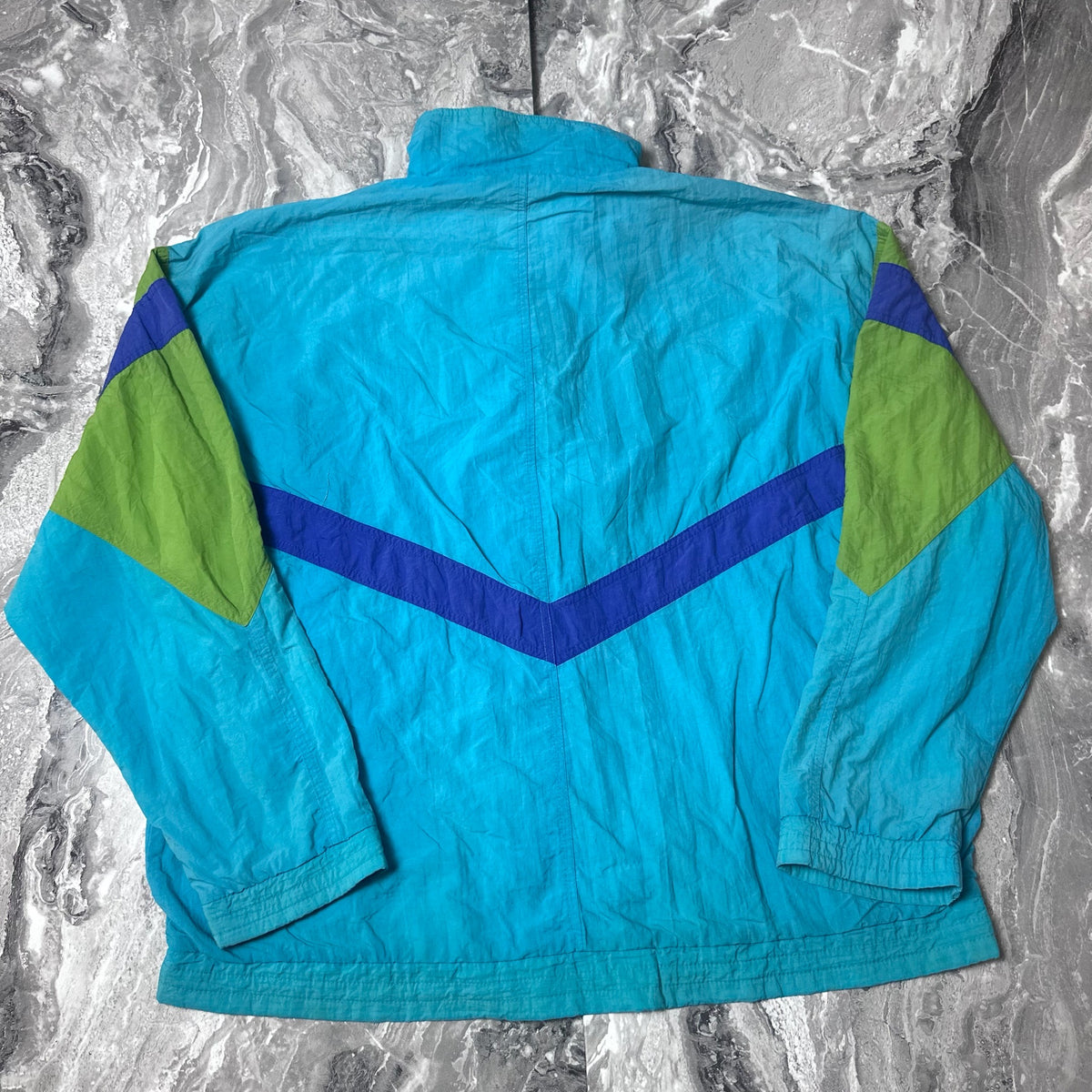Dos de la veste Puma vintage bleue avec motifs verts et violets