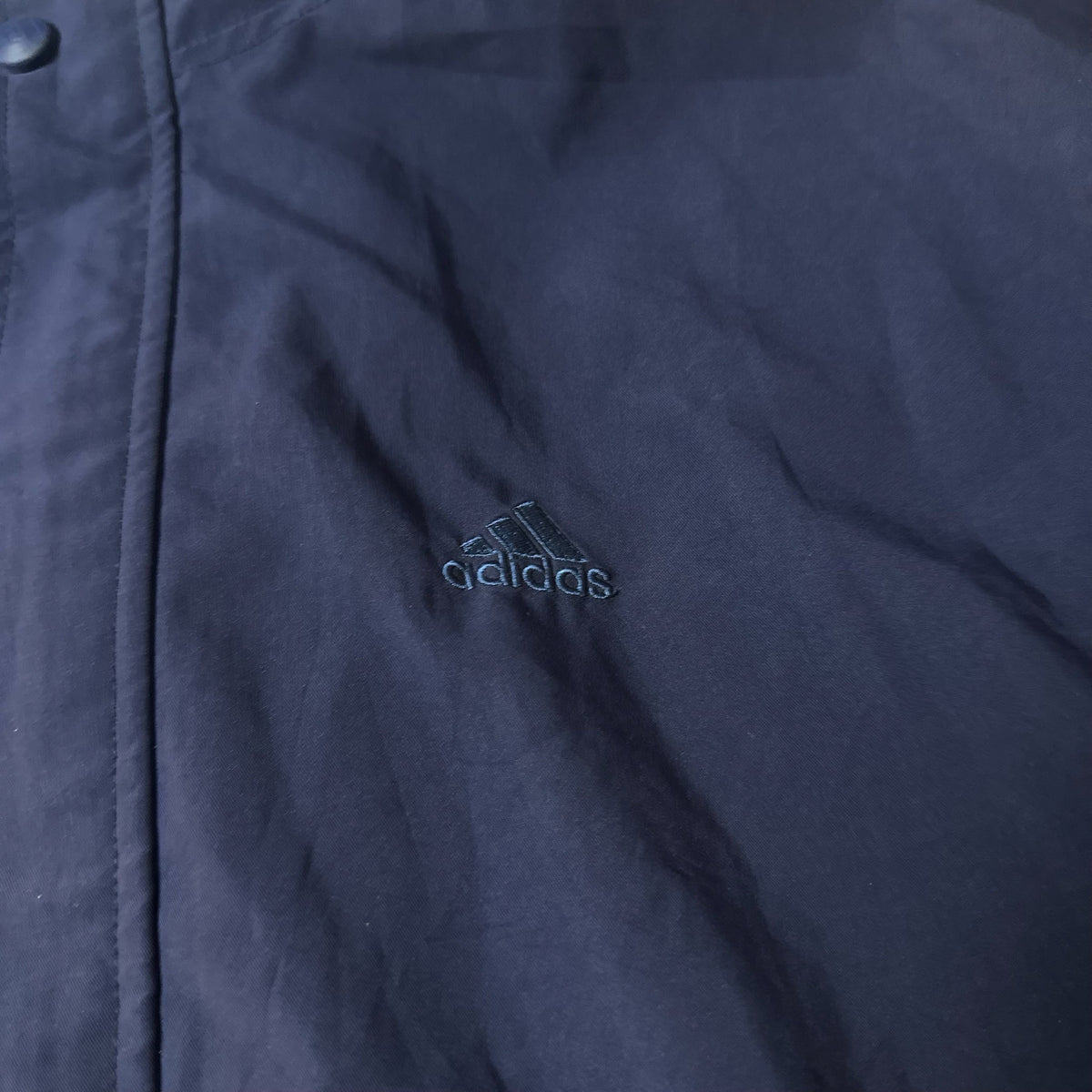 Détail logo brodé Adidas sur veste golf bleu marine