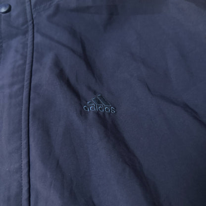 Détail logo brodé Adidas sur veste golf bleu marine