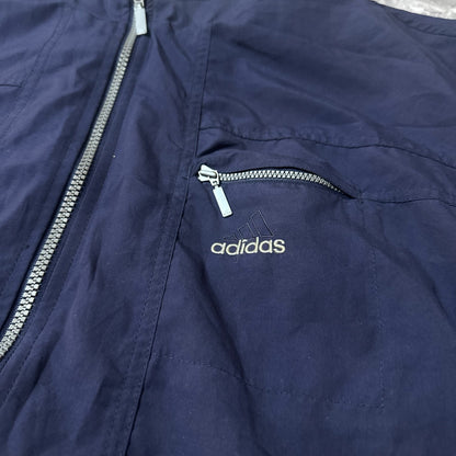 Détail de la poche zippée et broderie logo Adidas sur la veste bleu marine