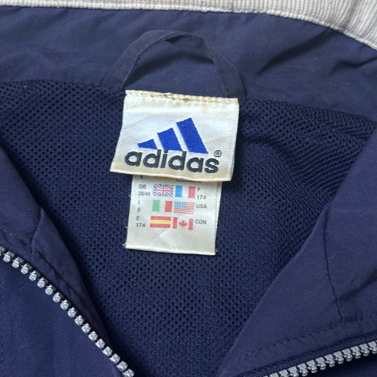 Détail de la manche avec bord côte beige de la veste Adidas