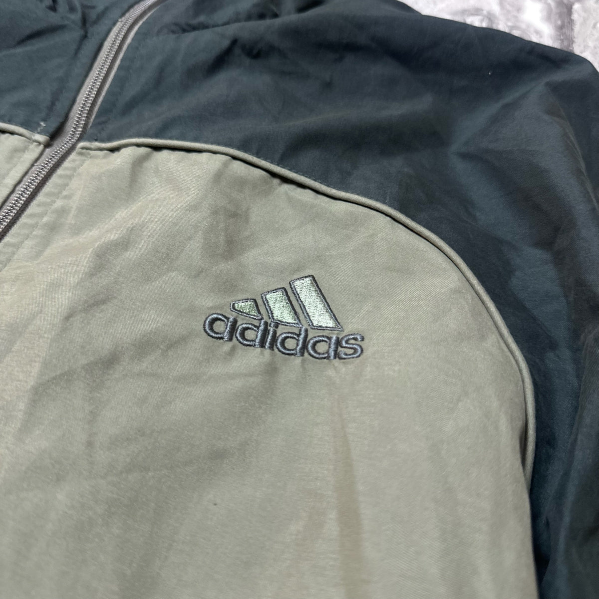 Gros plan sur le logo Adidas brodé sur la veste kaki et noire