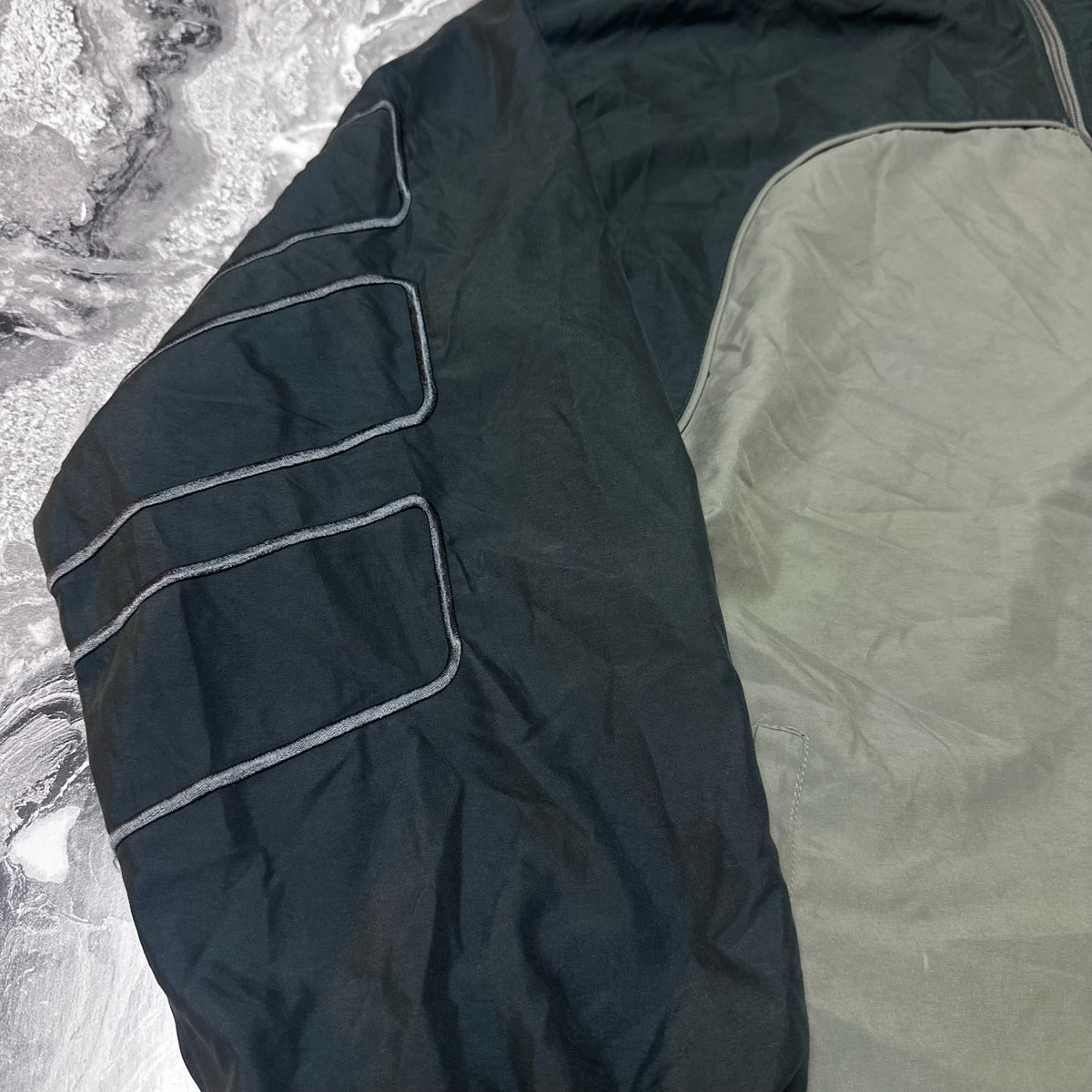Détail des motifs brodés sur la manche noire de la veste Adidas