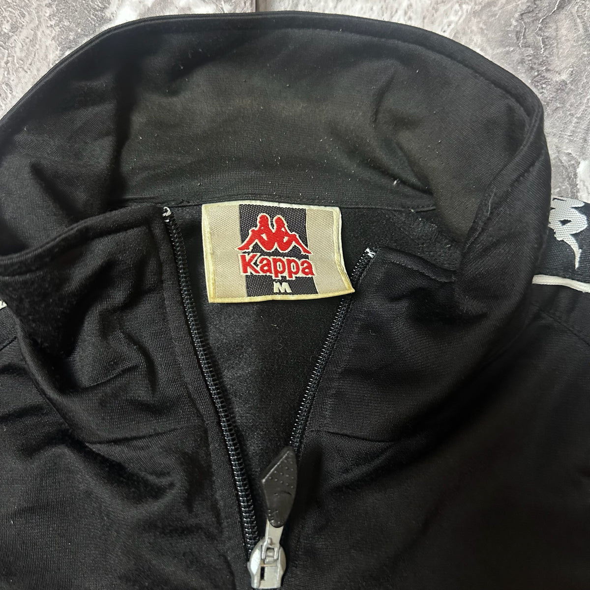 Détail des bandes logo Kappa sur les manches de la veste noire