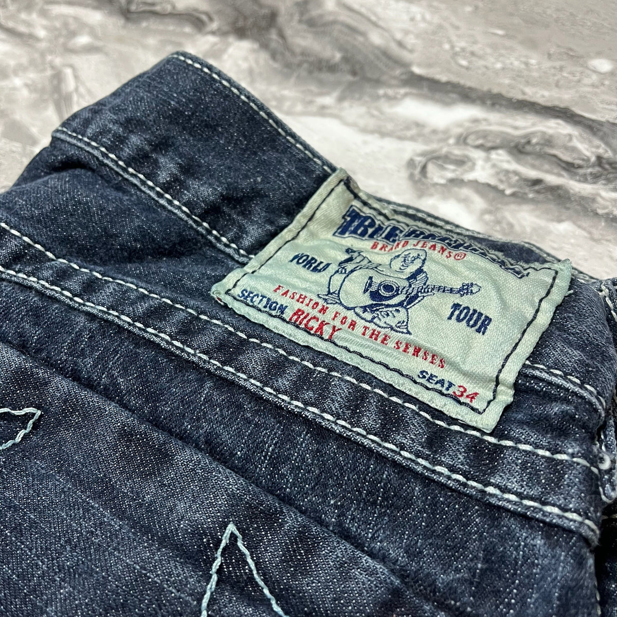 Étiquette True Religion blanche bleue et rouge sur jean