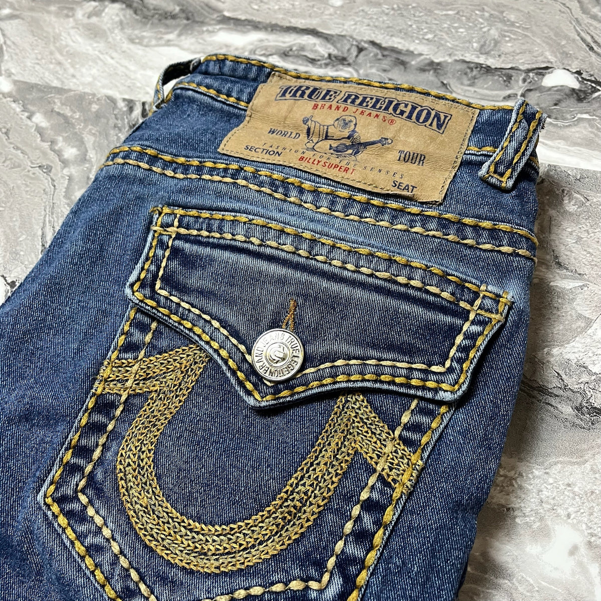 Détail de la poche arrière jean True Religion avec broderie fer à cheval et bouton